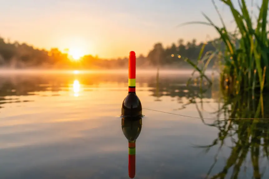 Flotteur de pêche au coup rouge et jaune parfaitement équilibré sur une eau calme au lever du soleil