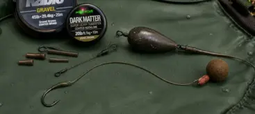 Montage complet de pêche à la carpe avec hameçon bouillette et plomb posé sur tapis de réception